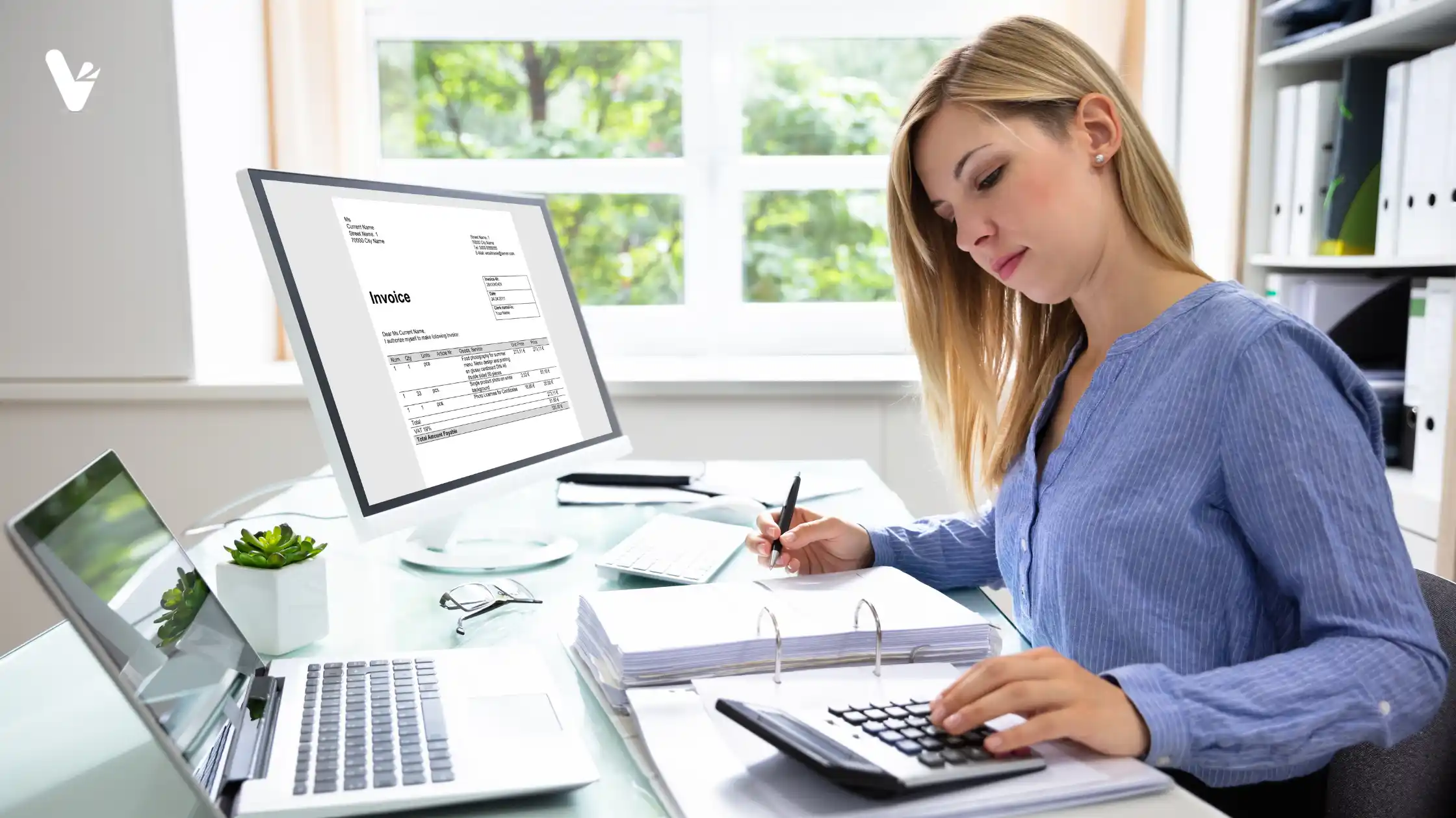 A blonde woman working on her computer, paperwork, and a calculator in an office.