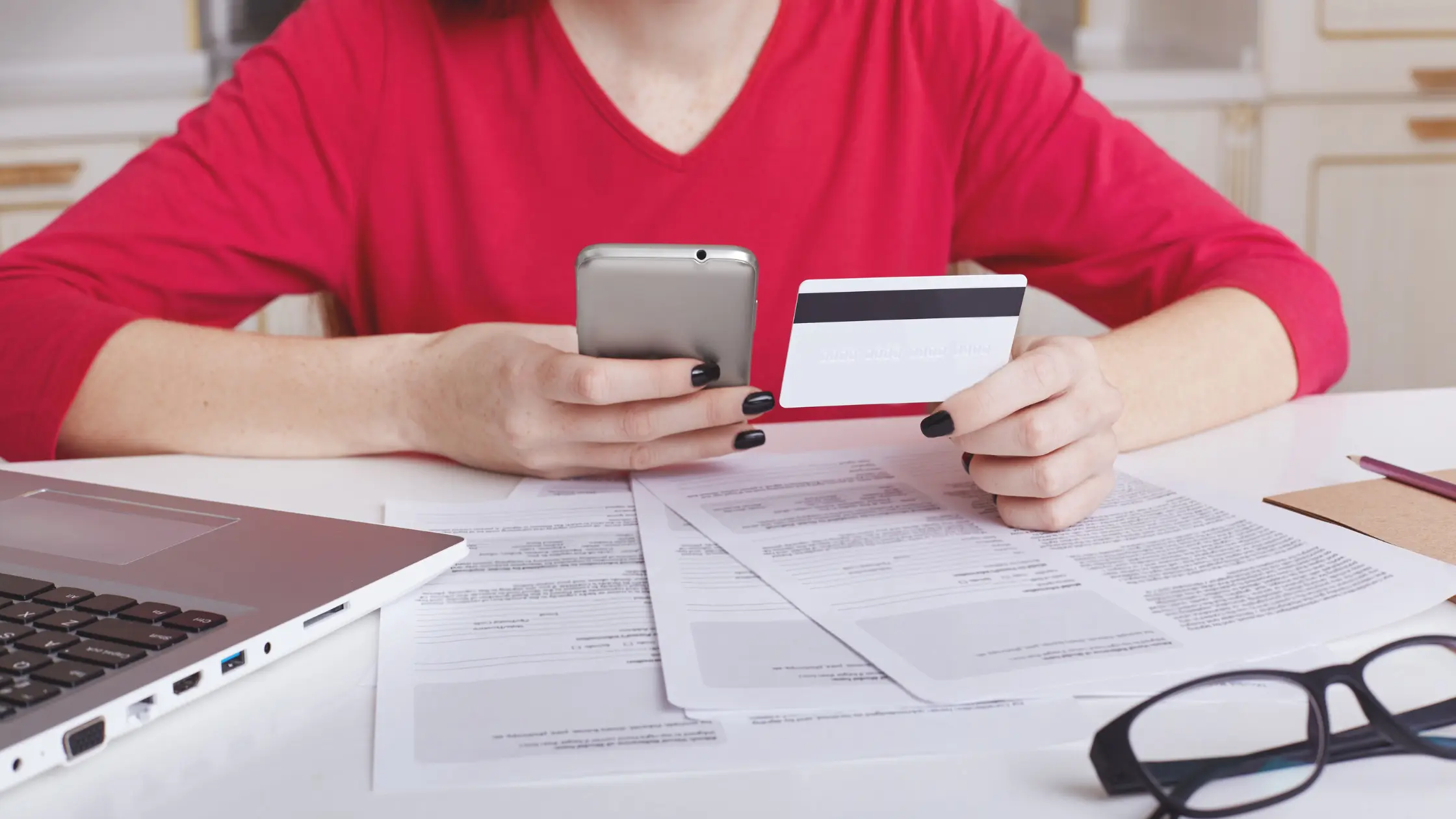 Woman using phone, credit card for quick soft credit check.