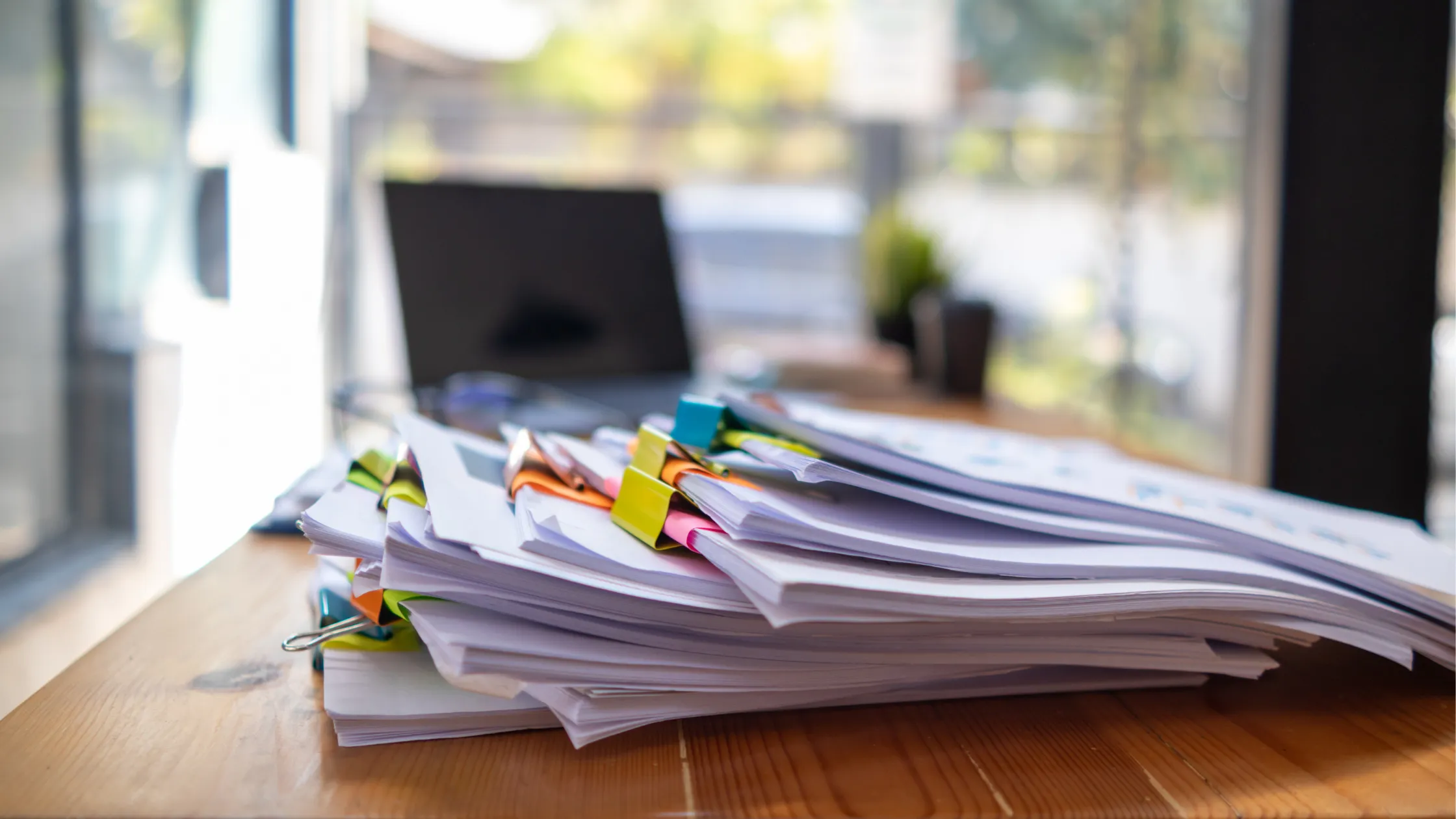 Stack of compiled business loan documents on a wooden desk.