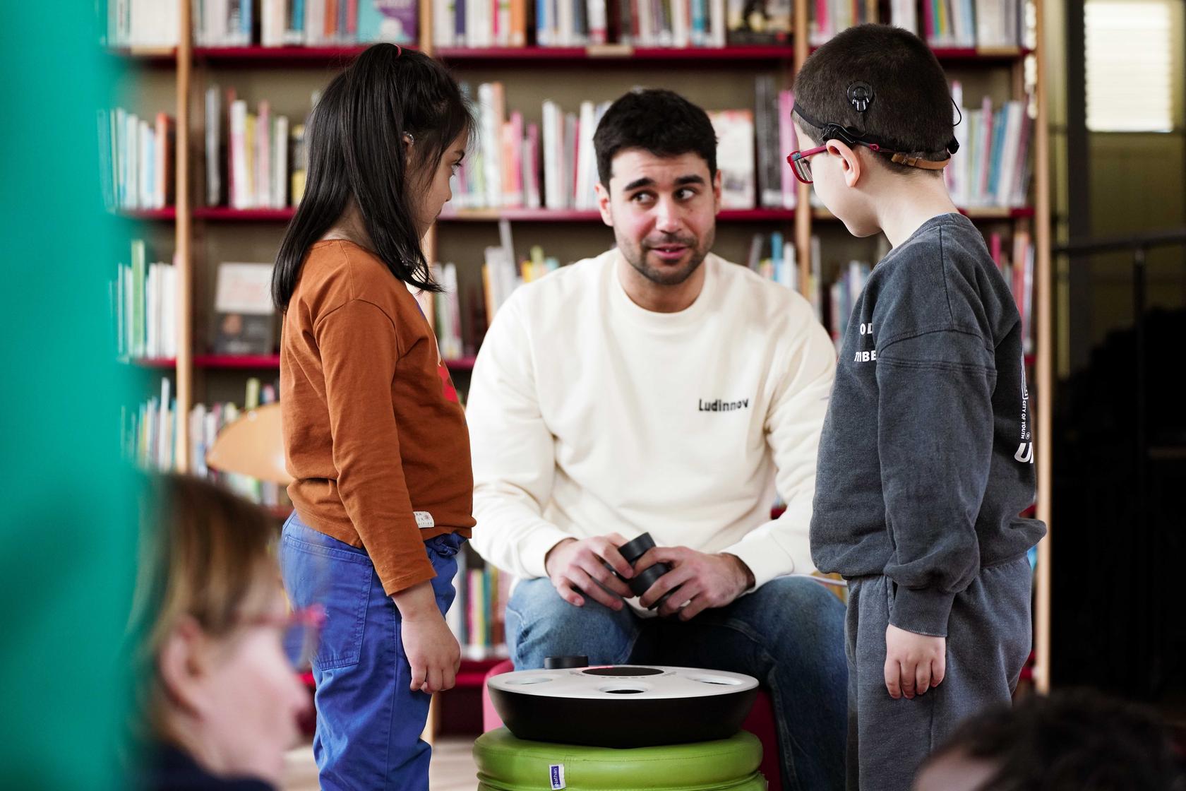 Une personne de l'équipe Ludinnov présentant le maestro à des enfants en situation de handicap dans une bibliothèque