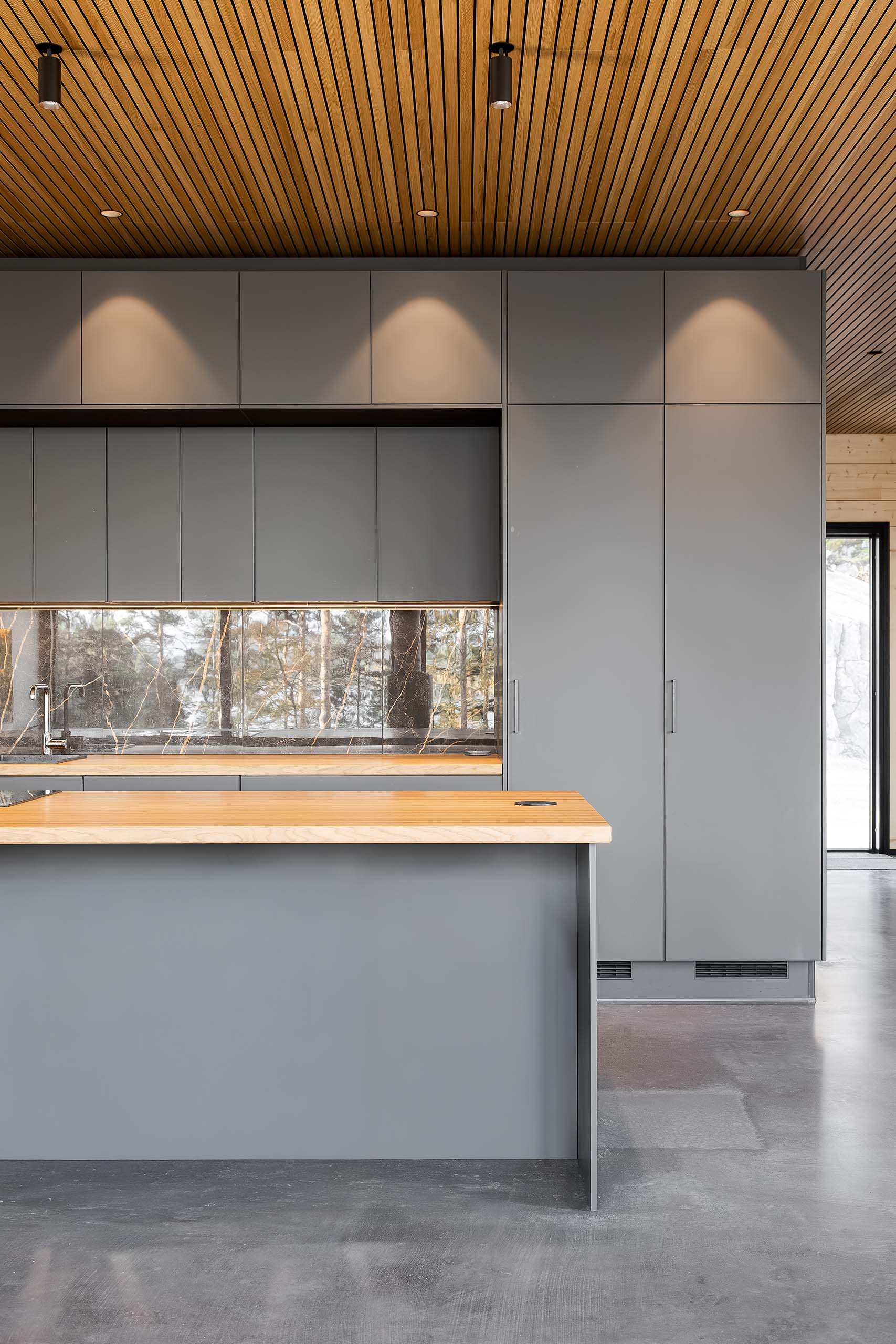 Modern kitchen with gray cabinets, wooden ceiling, and wooden countertop island with built-in outlet.