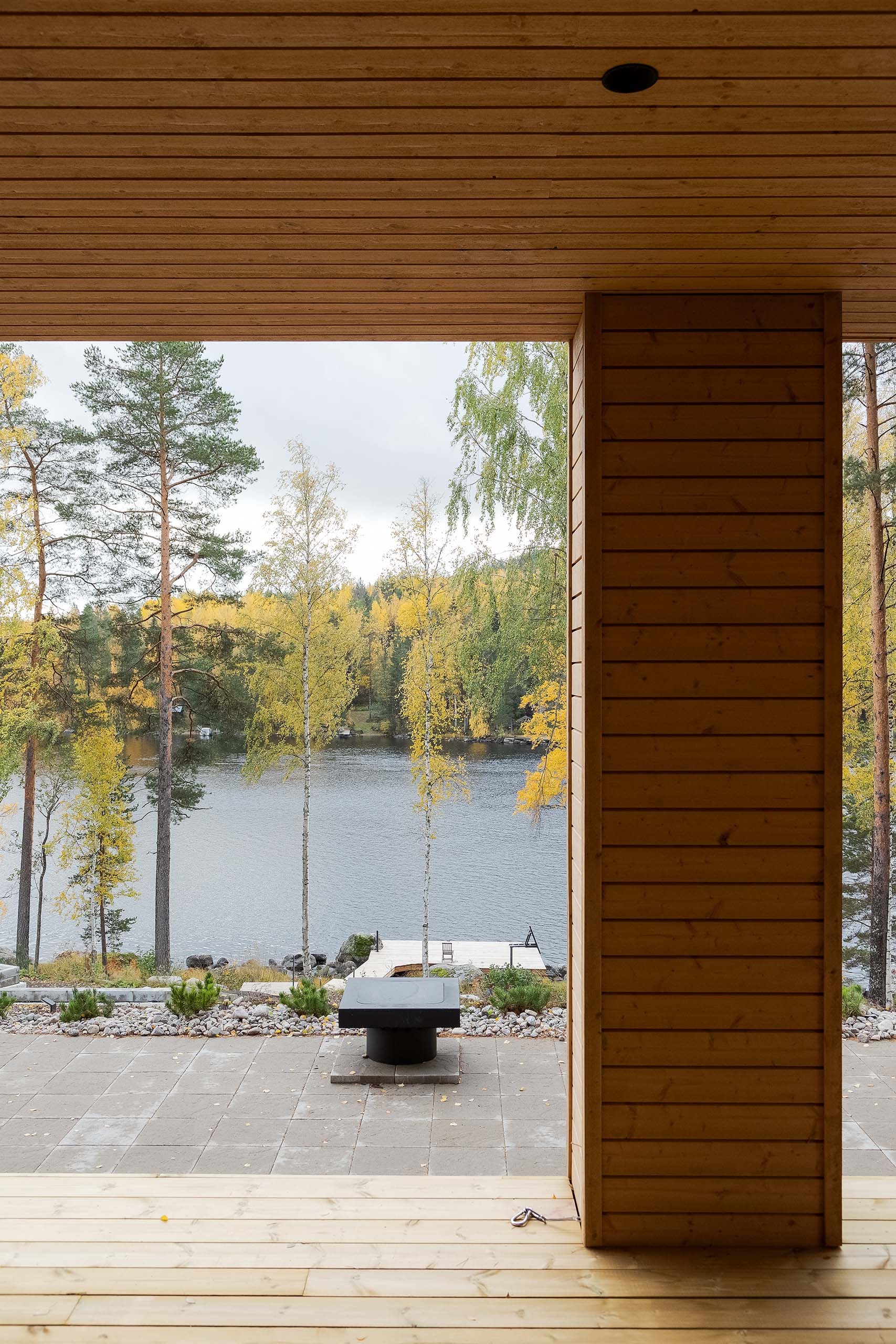 View from a wooden porch overlooking a lake with autumn trees and a small dock.