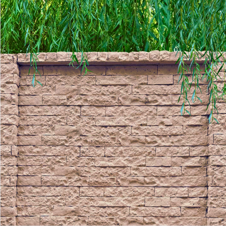 A close-up view of a pinkish-brown precast concrete fence panel with a rough brick texture and cap. Green, leafy branches from a weeping willow tree hang over the top edge.