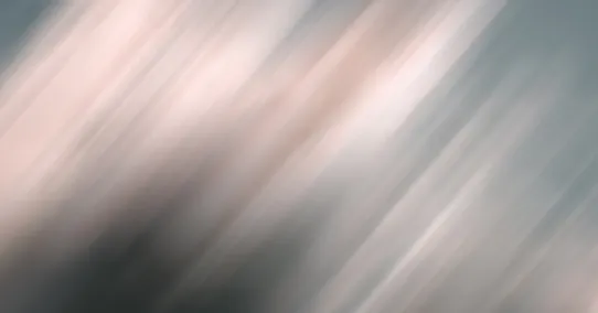 Abstract blurred background with diagonal streaks in soft pink, gray, and black tones.
