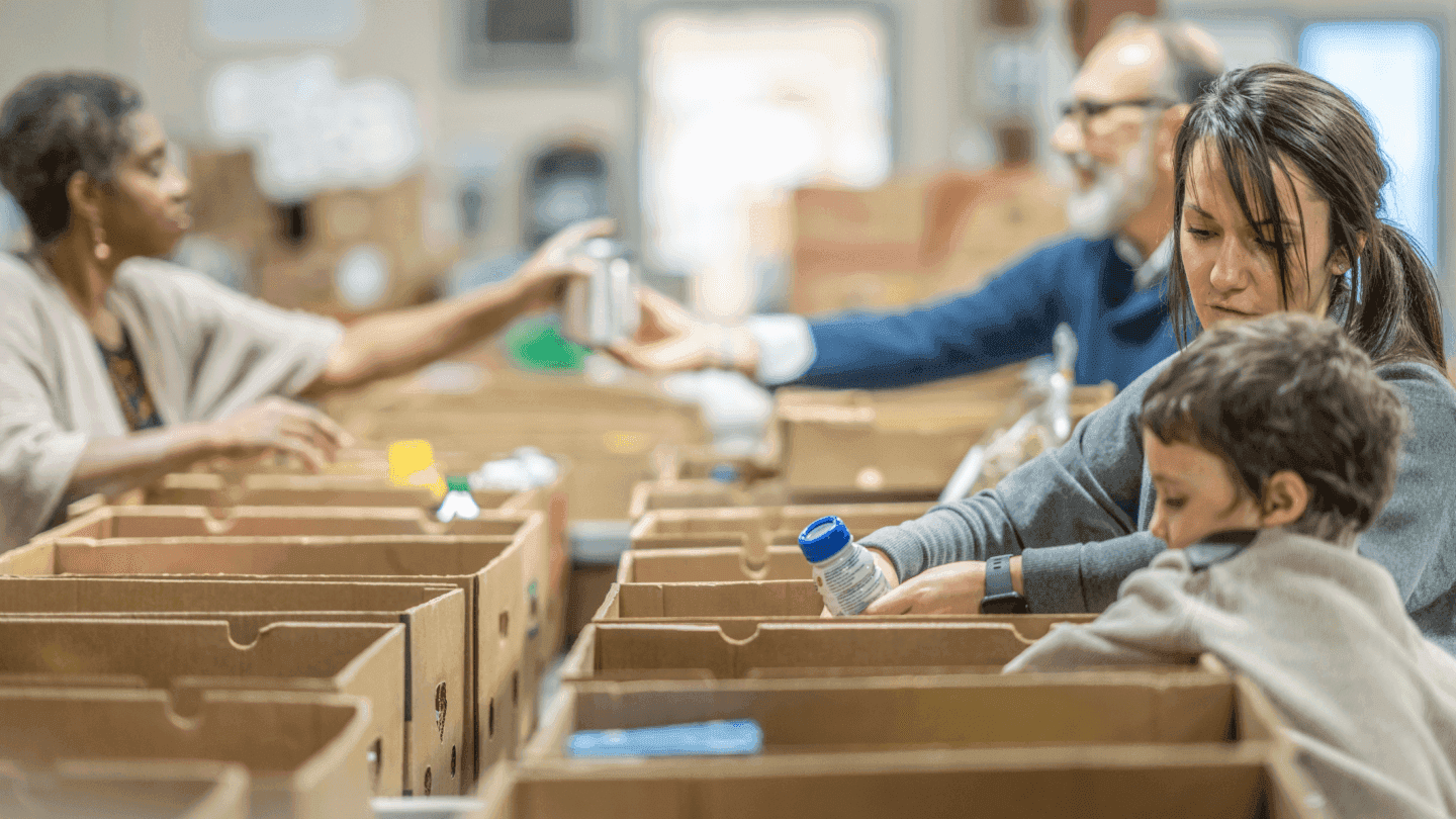 Volunteers packing food items into boxes at a community support center.