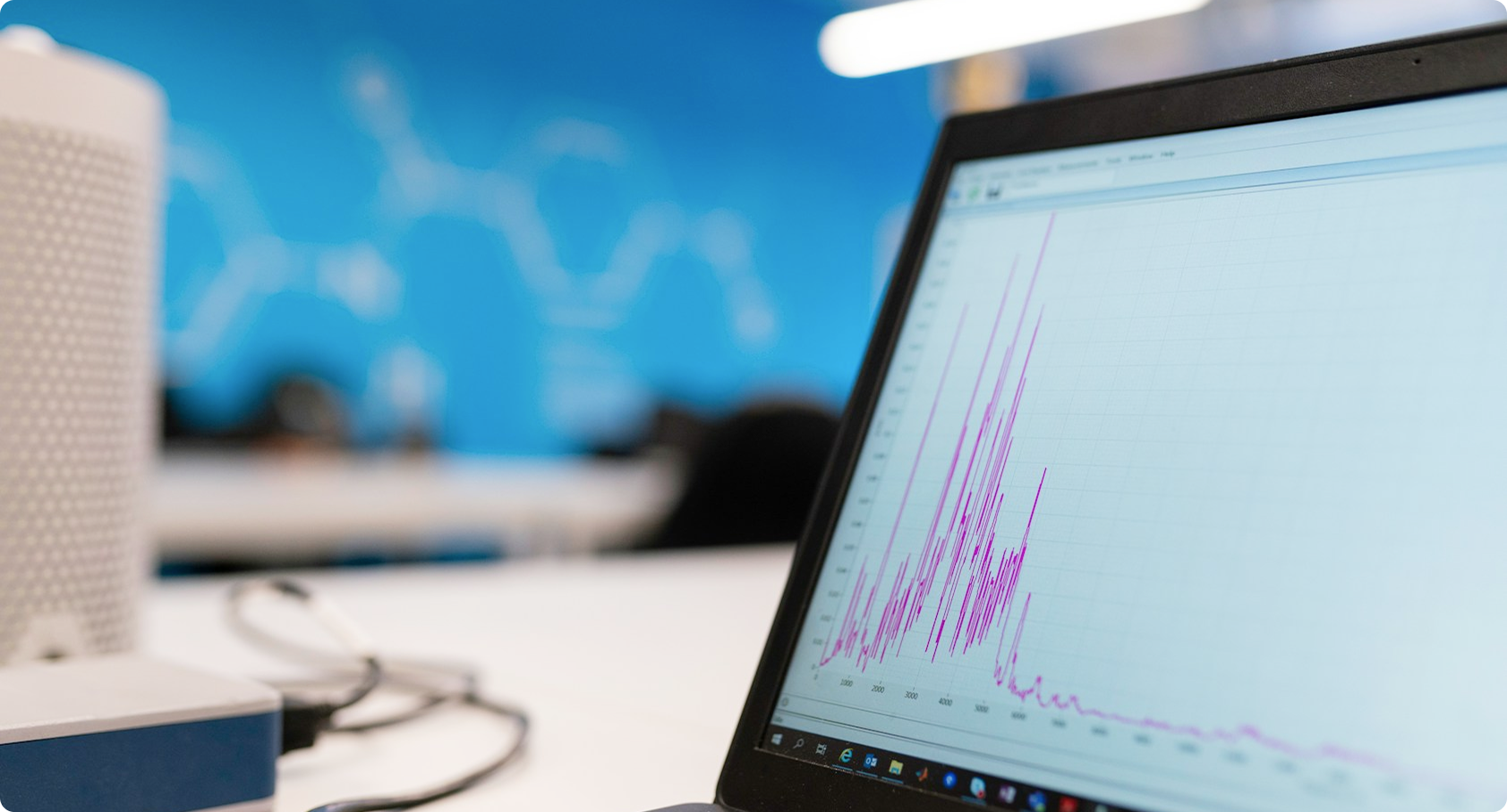 Laptop screen displaying a graph with multiple sharp peaks in purple lines on a grid background.