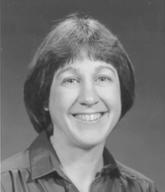 Black and white portrait of a smiling woman with short hair wearing a collared shirt.