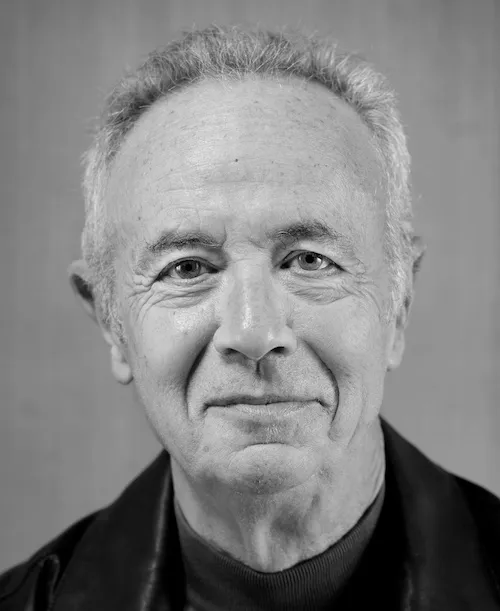 Black and white portrait of an older man with short gray hair wearing a dark jacket and shirt, looking calmly into the camera.