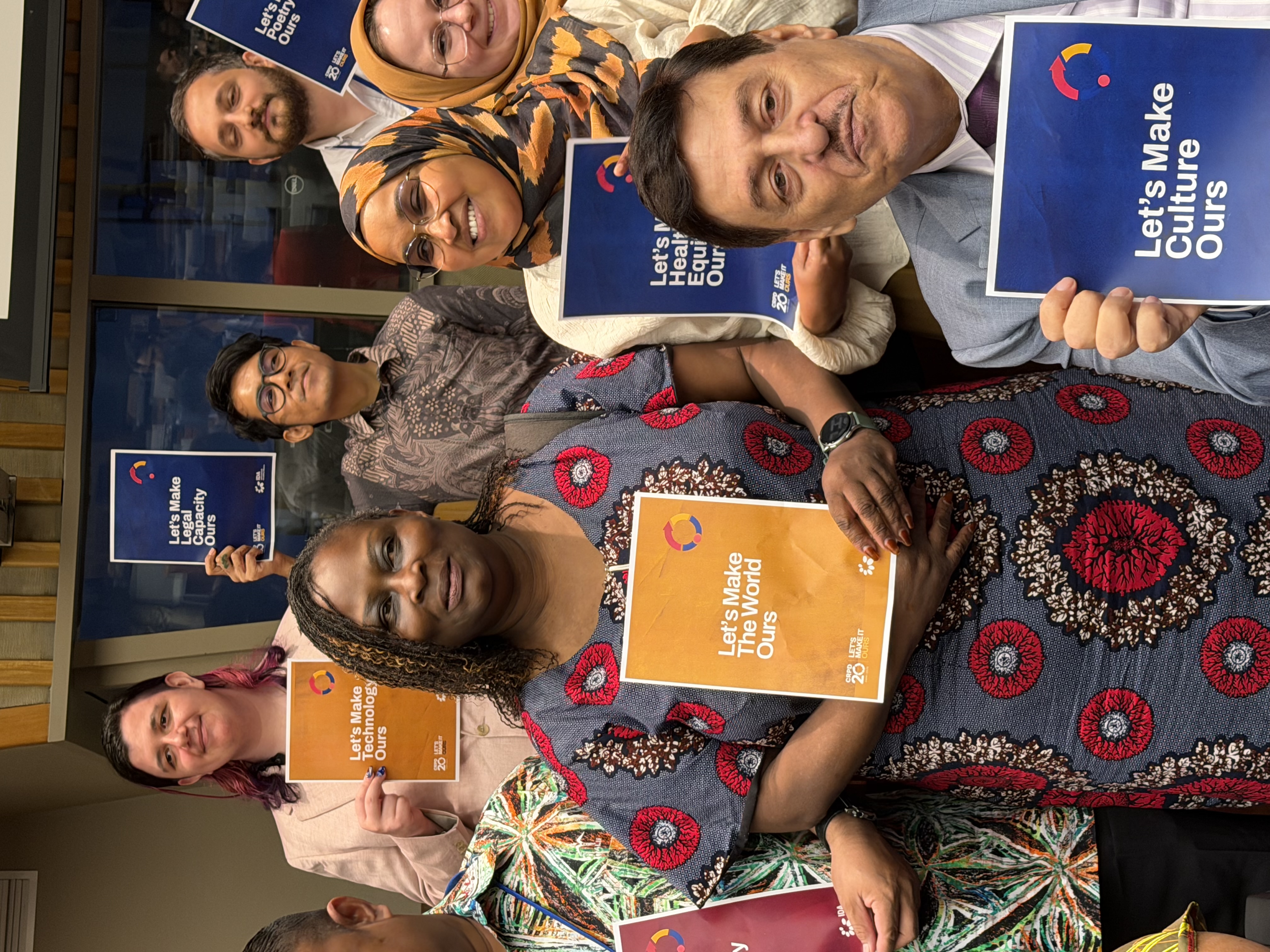 A group of persons with disabilities holding signs of the Lets Make It Ours campaign