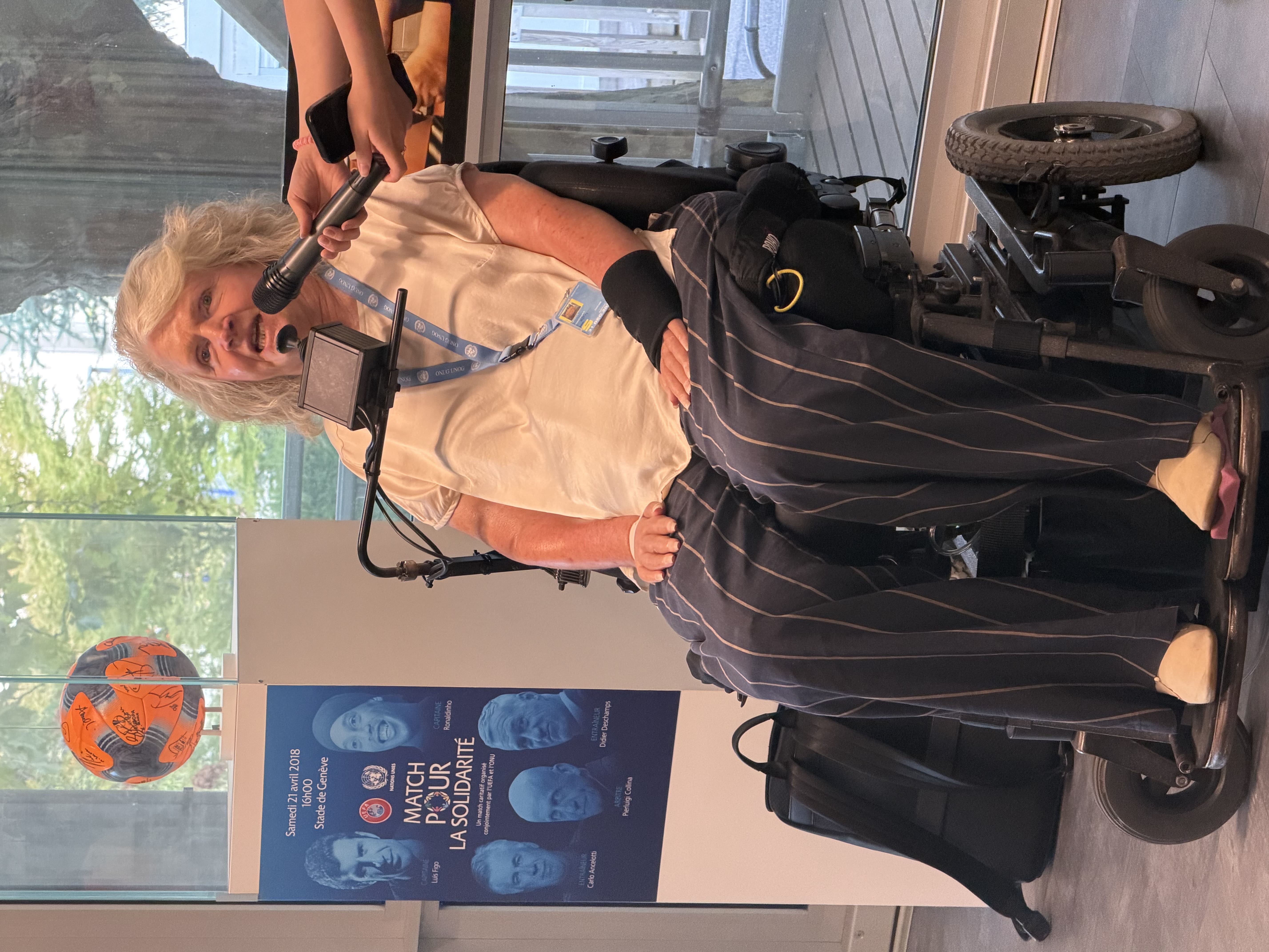 Rosemary Kayess , a wheelchair user speaking on a mic. Someone else is holding the mic for her.