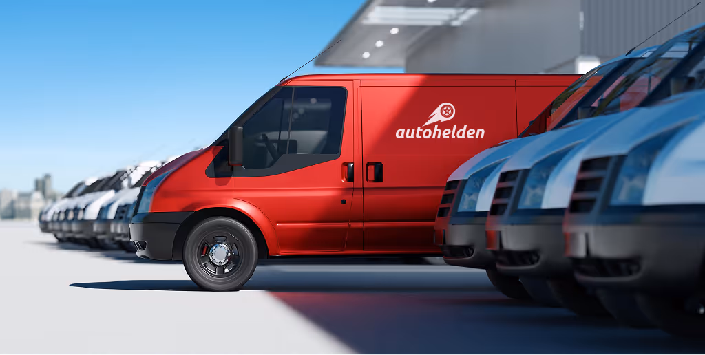 Row of white vans parked next to a single red van with the Autohelden logo on its side under a clear blue sky.