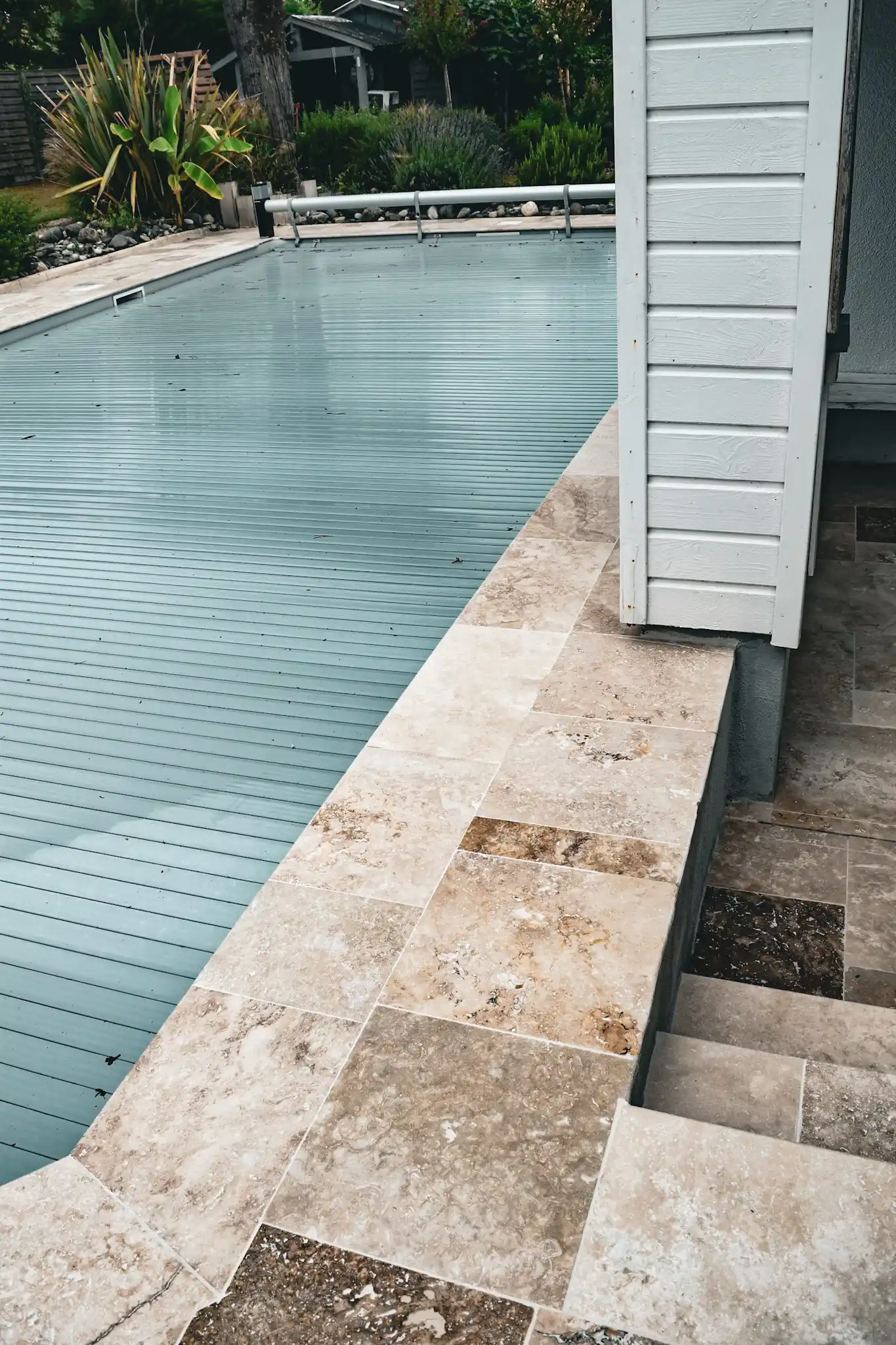 Terrasse en pierre naturelle autour d’une piscine avec aménagement paysager soigné
