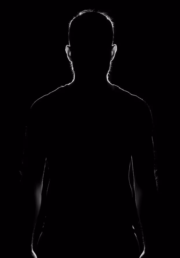 Mörk silhuett av en person mot svart bakgrund, kontrastrik belysning
