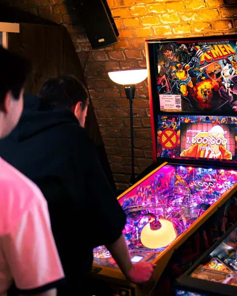 Gäste spielen an einem X-Men-Pinballautomaten.