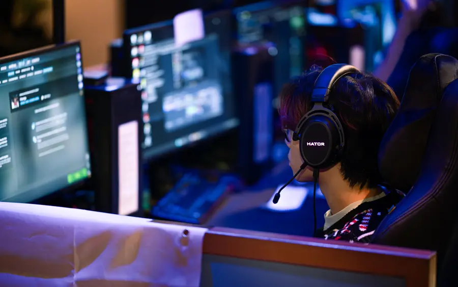 Person mit einem Headset sitzt vor einem PC
