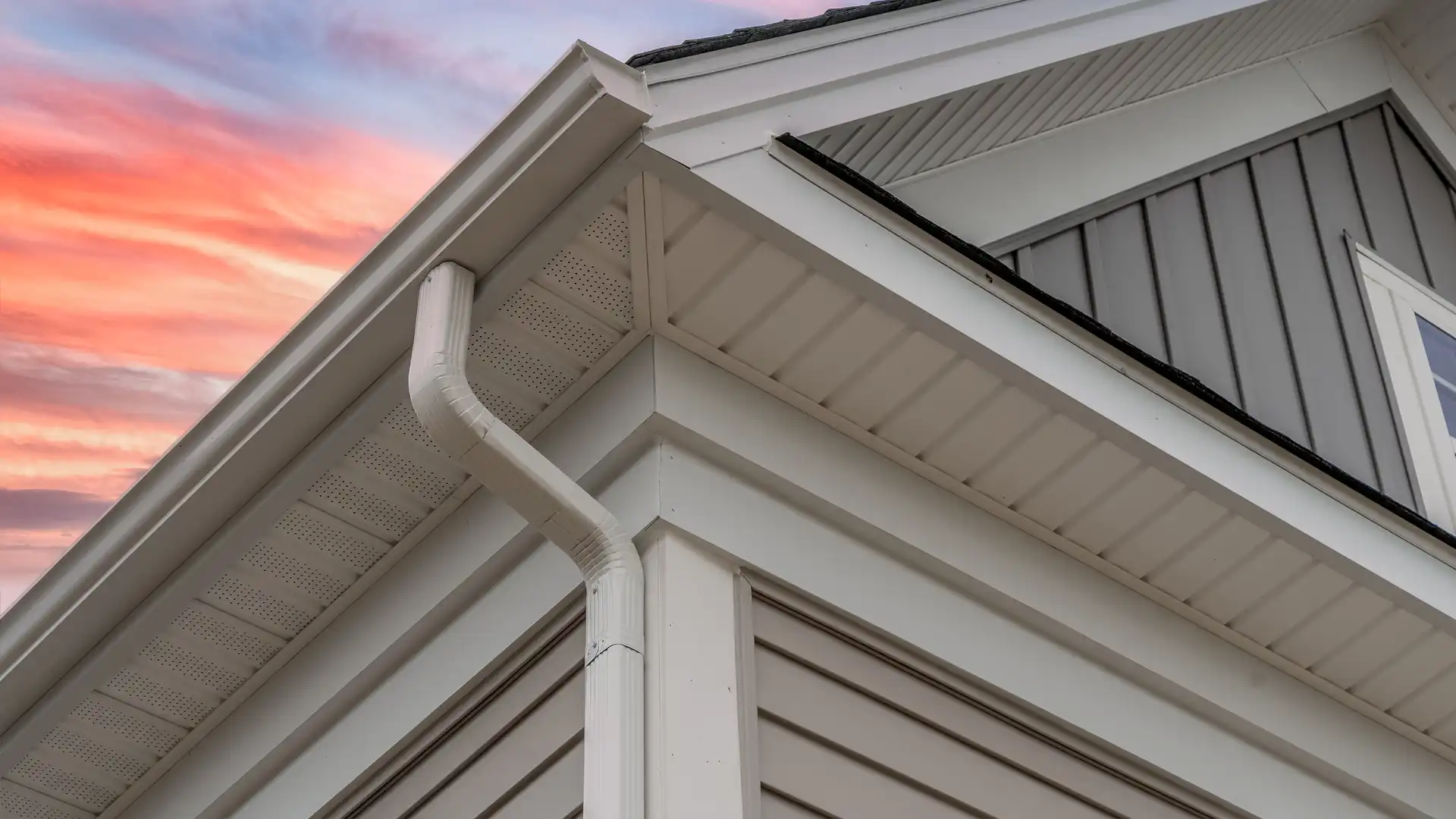 Close-up of white gutter and soffit on a home exterior at sunset