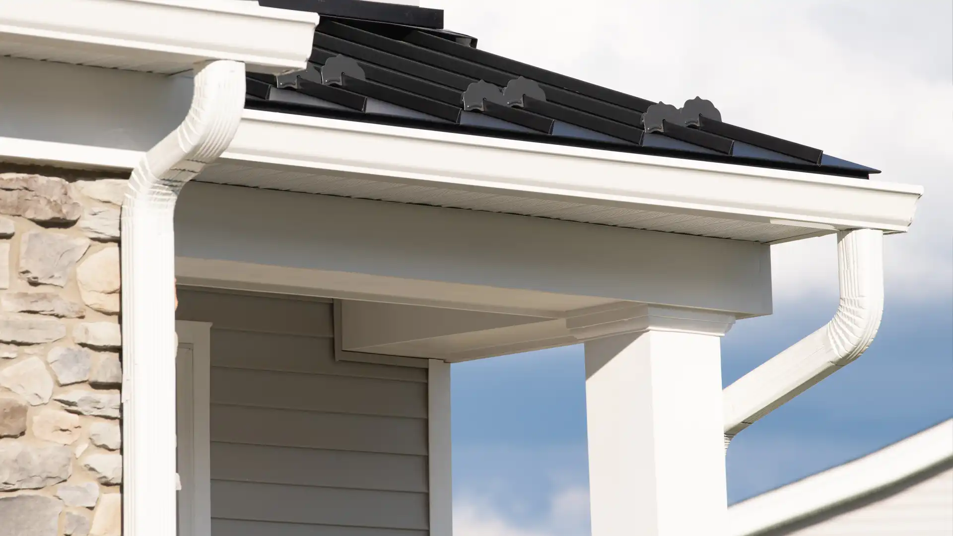 Close-up of white gutters and soffit along a home roofline with black roofing above