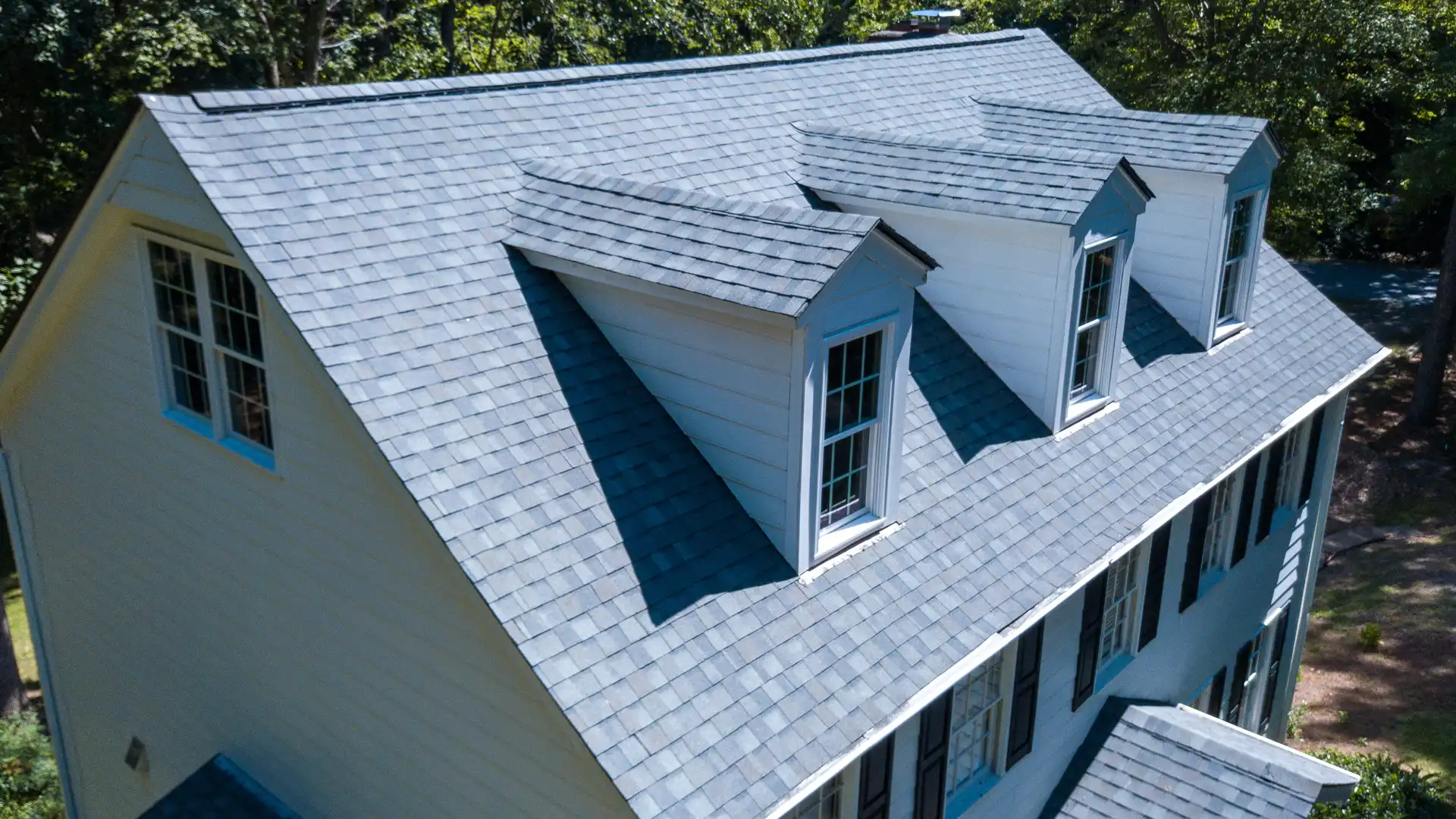 Aerial view of gray asphalt shingle roof with dormer windows on a residential home