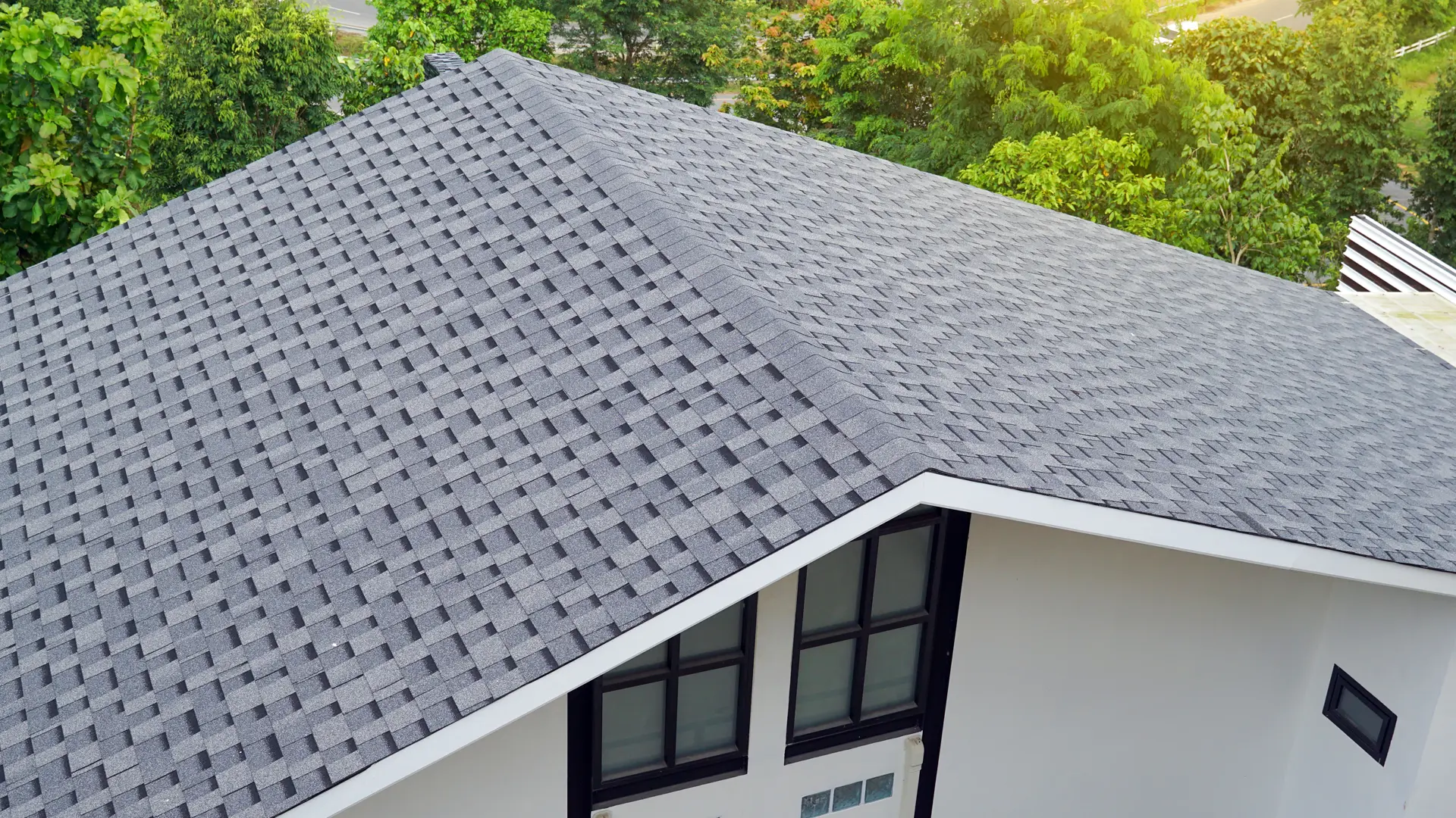 Gray asphalt shingle roof installed on a residential home with clean rooflines and surrounding trees
