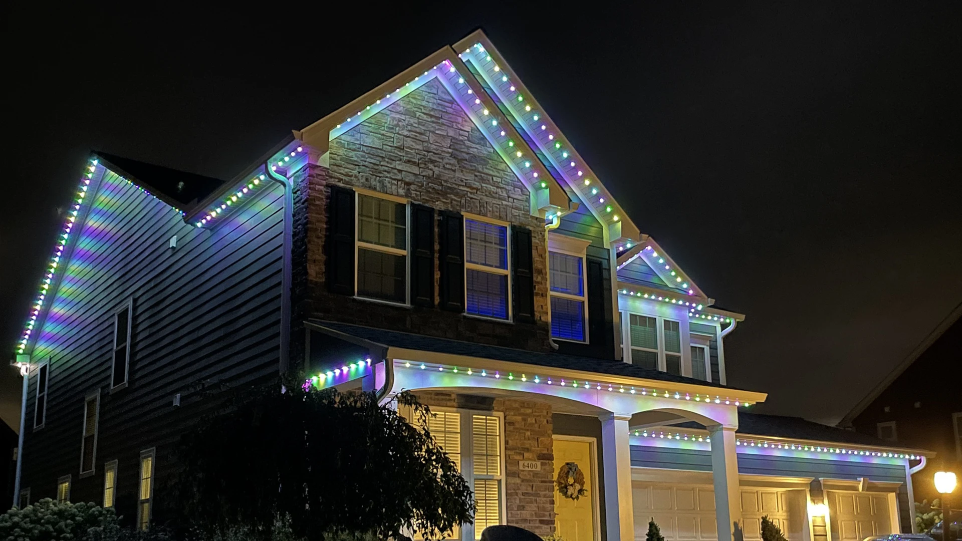 Two-story home at night with LED holiday lights installed along the roofline