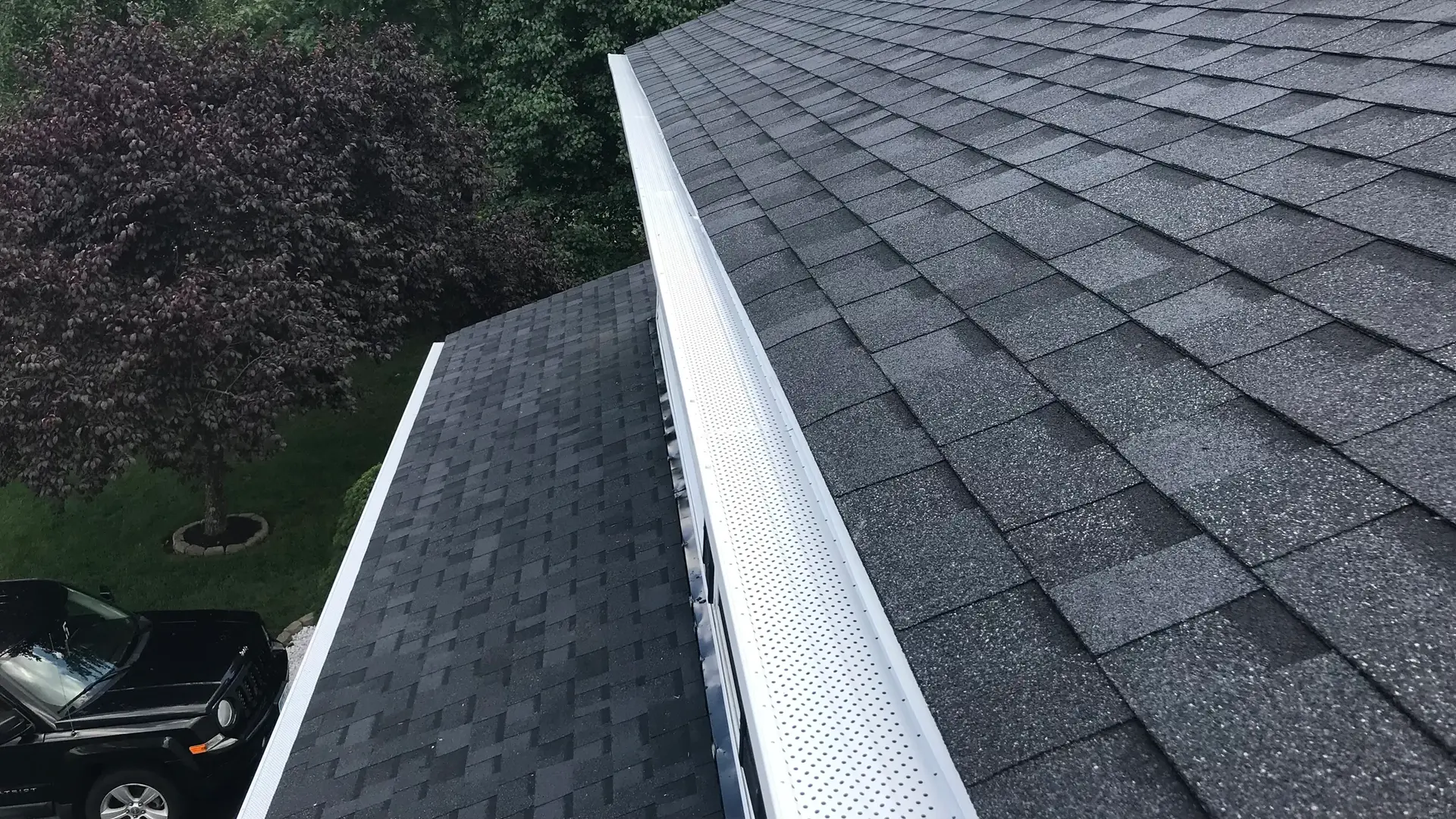 Roof gutter guard installed along asphalt shingles on a residential roof.