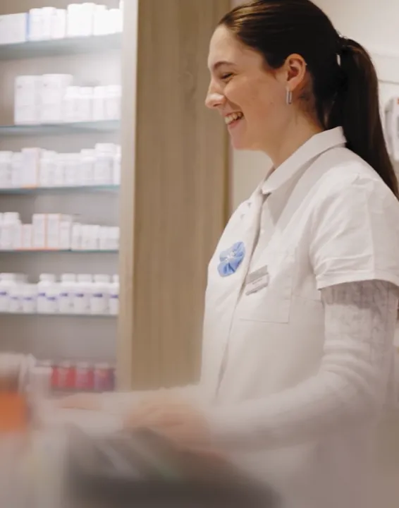 Ein Mann in Arbeitskleidung und Handschuhen spannt ein Seil an einem Holzzaun in einem Stall.