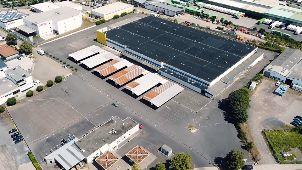 Luftaufnahme eines Industriegebiets mit verschiedenen Lagerhallen und Parkflächen.