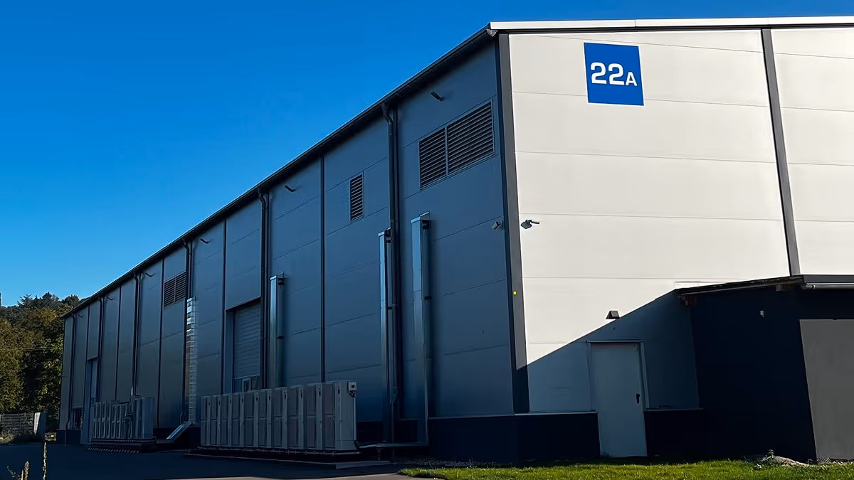 Gewerbehalle mit weißer Fassade und blauer Nummer 22A unter klarem blauem Himmel.