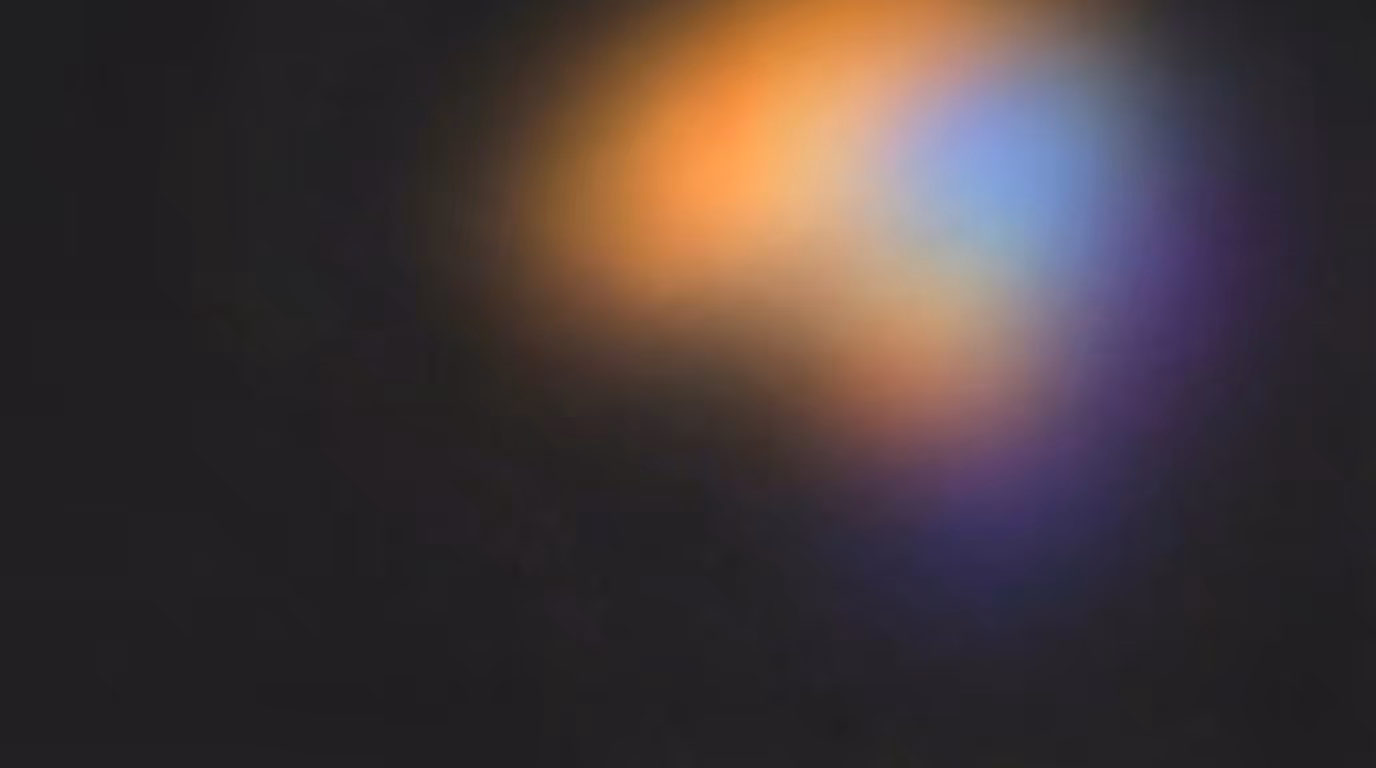 Soft, blurred light spots in warm orange, blue, and purple on a dark background.