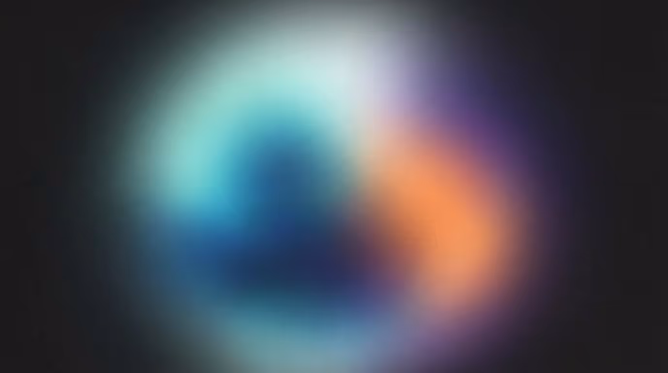 Blurred colorful circular shape with blue and orange tones on a dark background.