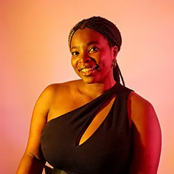 Smiling woman with braided hair wearing a black one-shoulder top against a gradient orange and purple background.