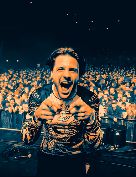 male performer pointing at the camera with a crowd in the background at a concert.