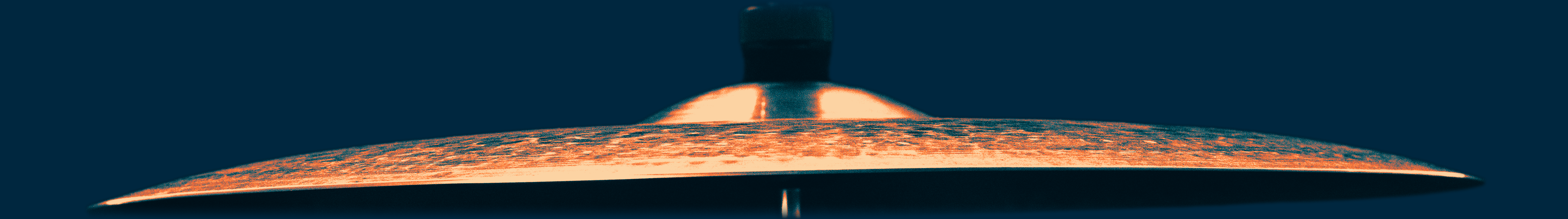 Close-up side view of a hi-hat cymbal against an orange background.