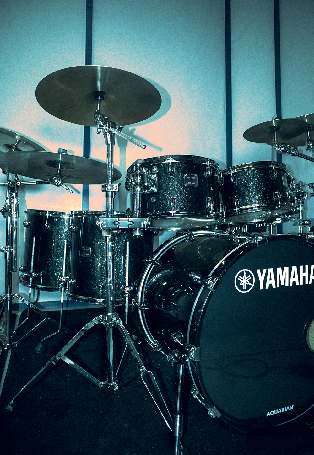 Black Yamaha drum set with multiple drums and cymbals arranged on chrome stands in a room.