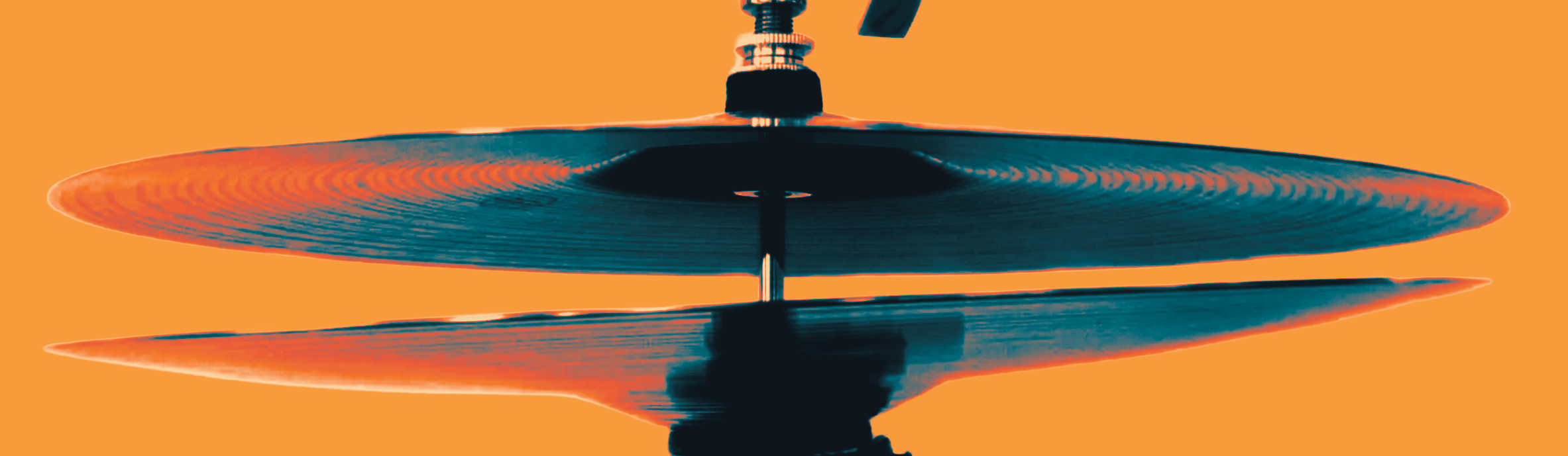 Close-up of stack of two hi-hat cymbals with orange background.