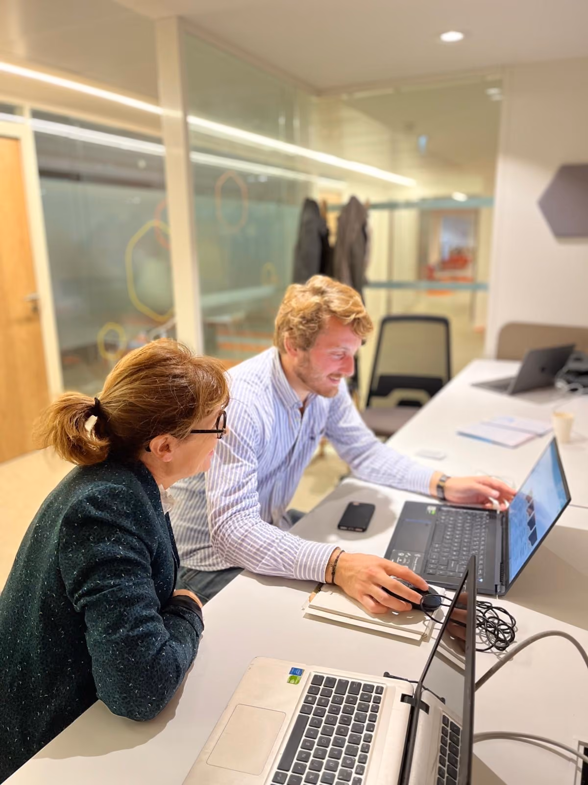 Deux membres Pleinia autour d'un bureau avec un ordinateur dans bureau moderne