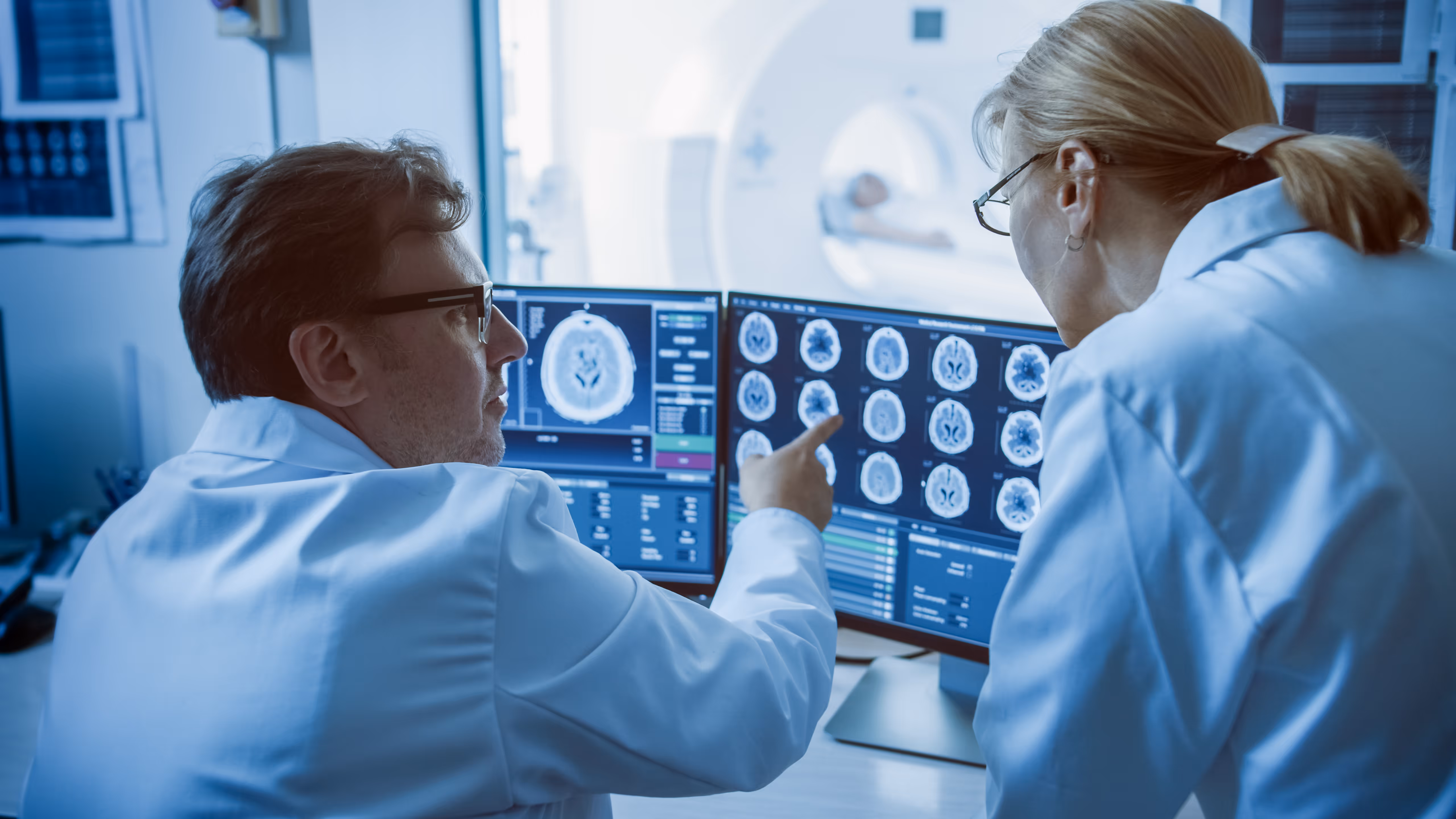 Two physicans discuss some medical images displayed on a computer screen.