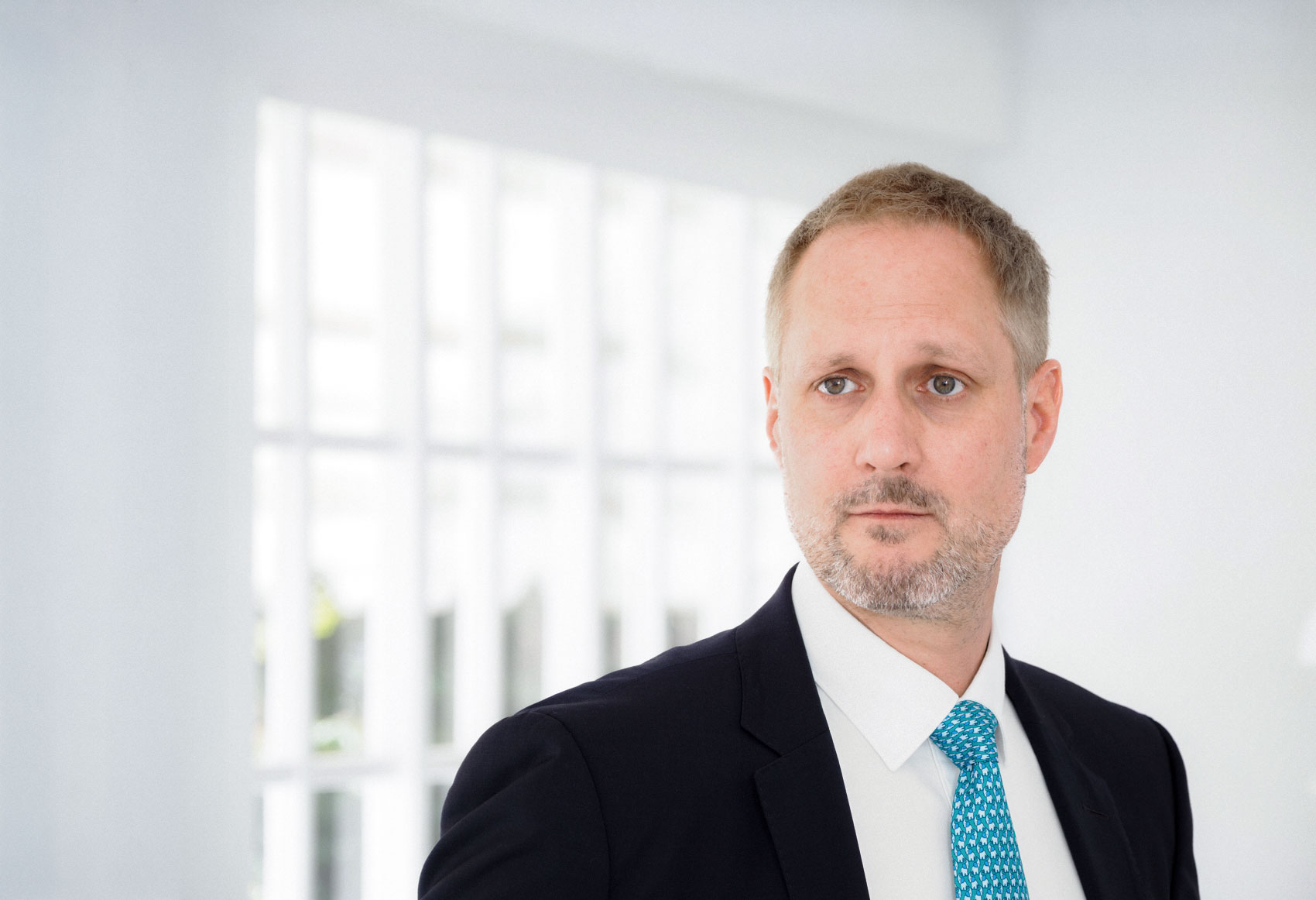 Ein Mann schaut kompetent in die Ferne. Er trägt einen Anzug.