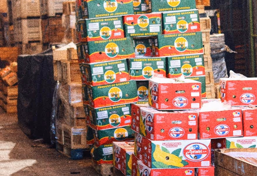 Stacks of colorful cardboard boxes labeled as premium and super premium bananas in a warehouse.