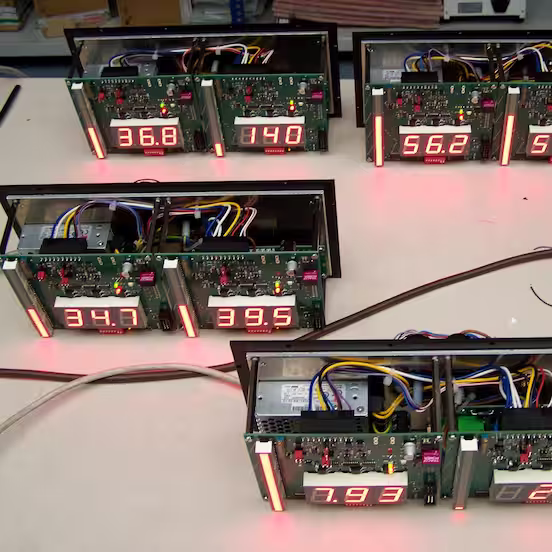 Opened display housings on a workbench with circuit boards, cables and red digit displays