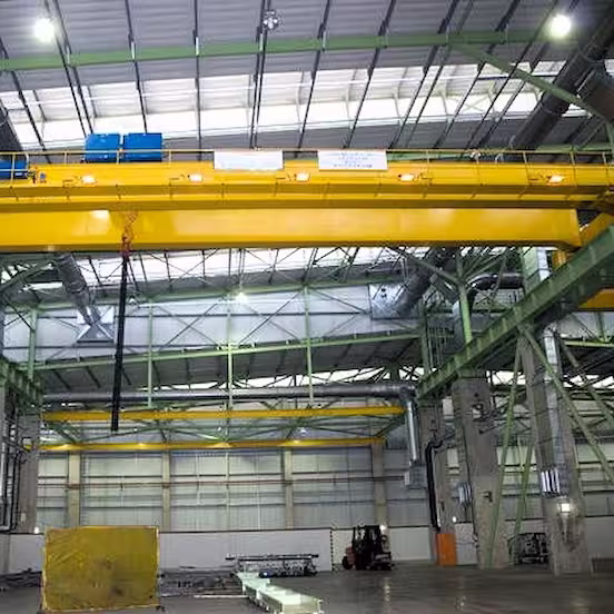 Industriehalle mit gelbem Laufkran, Stahlkonstruktion, Deckenleuchten und Gabelstapler
