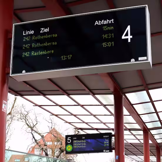 Abfahrtsanzeige mit Linie, Ziel und Abfahrtszeiten unter einem roten Bahnsteigdach