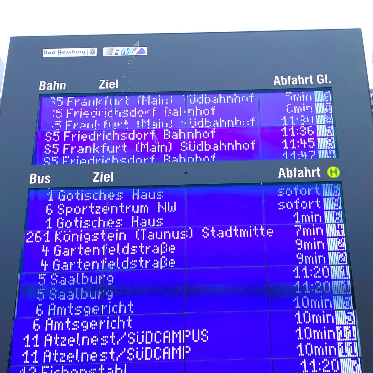 Close-up of a blue display board with separate sections for train and bus departures