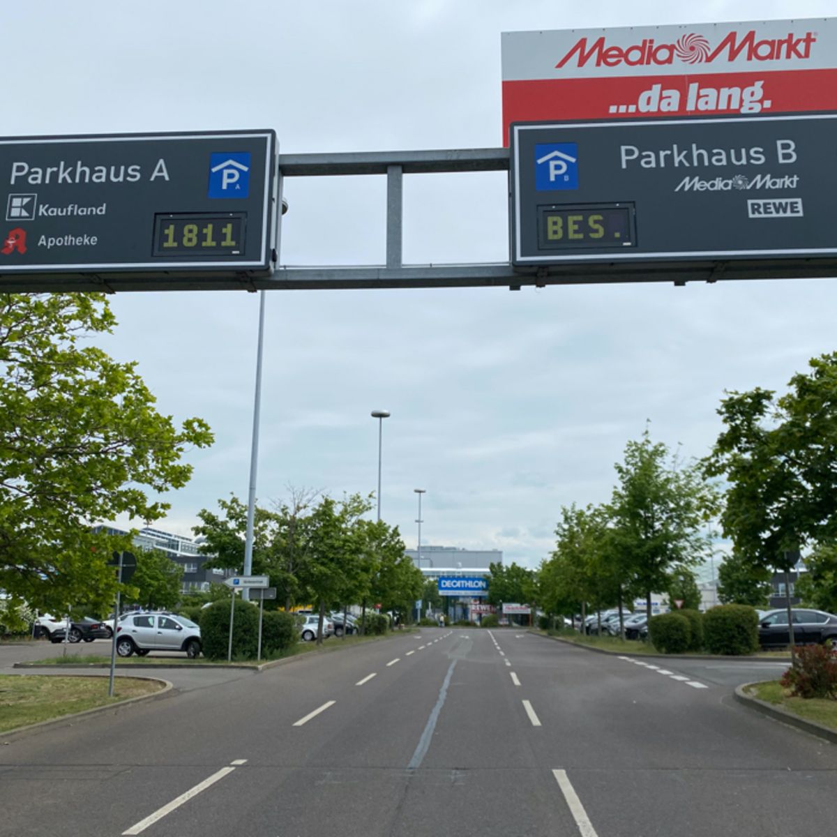 Überkopfschilder für zwei Parkhäuser mit gelben LED-Anzeigen freier Plätze über einer Zufahrtsstraße