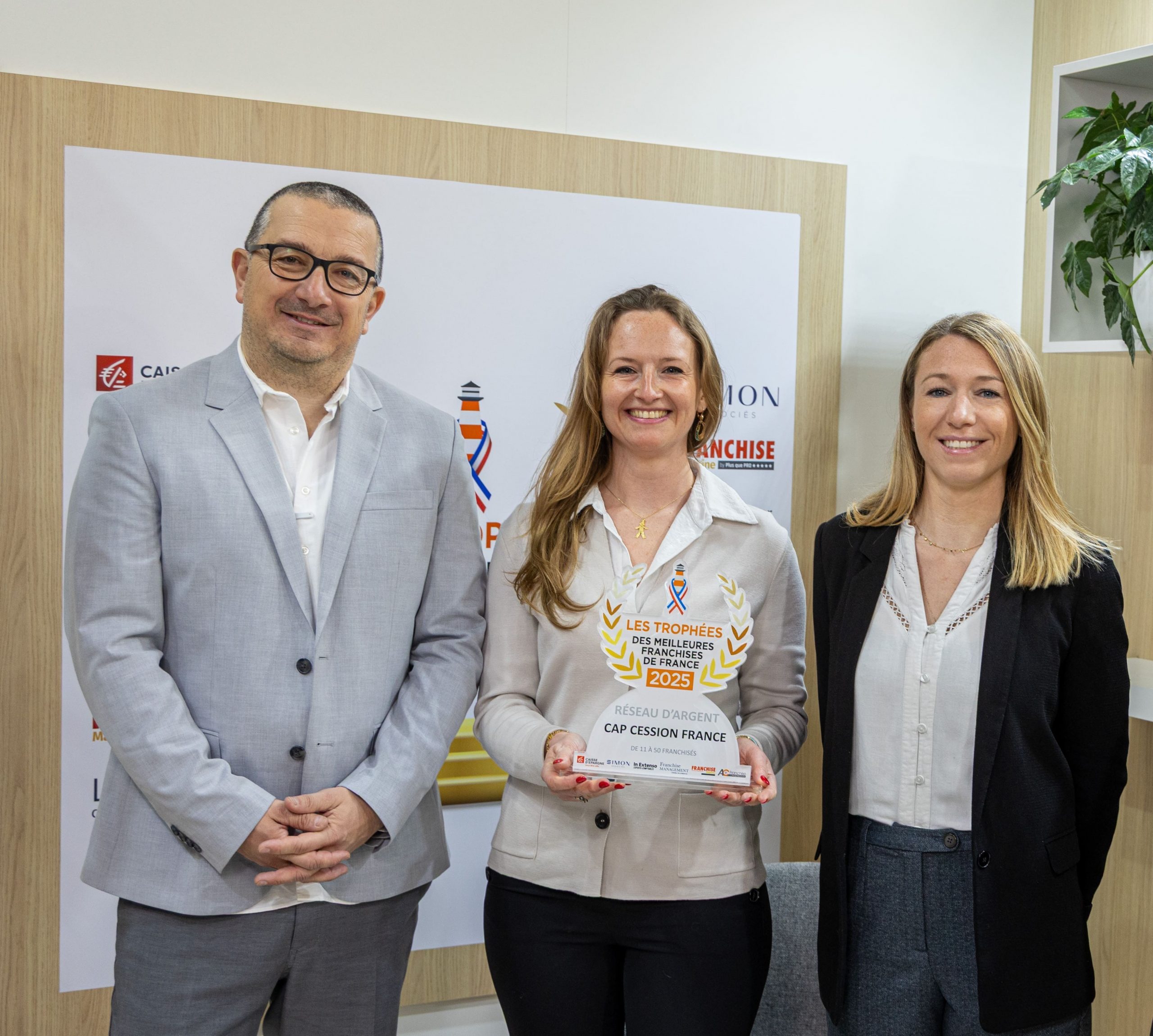 Trois membres de Cap Cession France posant avec le trophée Réseau d'Argent des Meilleures Franchises de France 2025