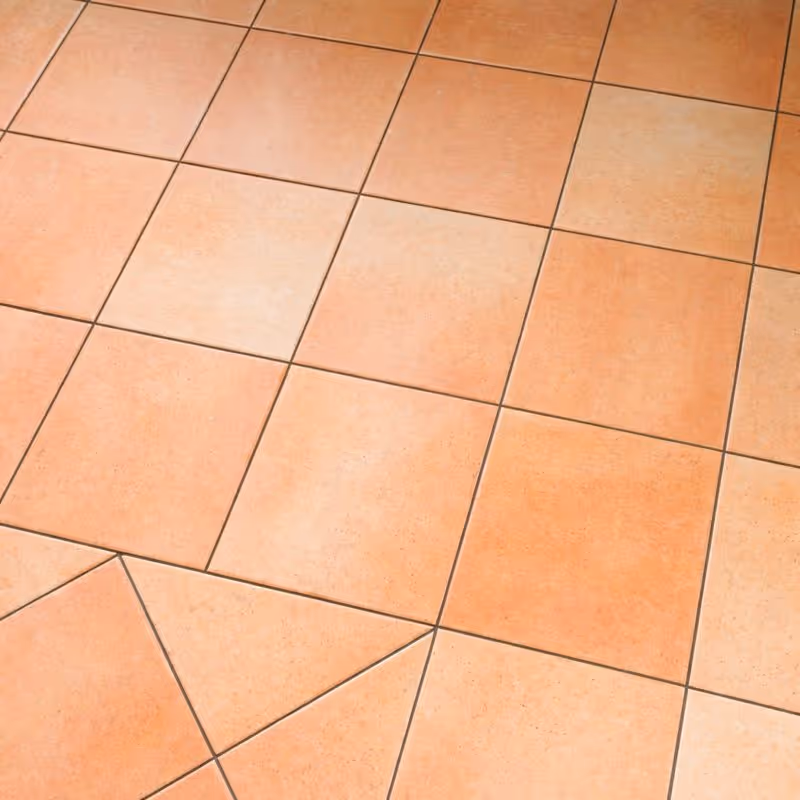 Nahaufnahme von Terrakotta-Bodenfliesen, die in einem Rastermuster mit warmen Orangetönen angeordnet sind.