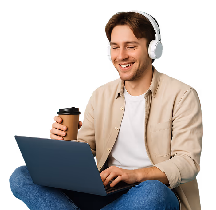 A young man sitting with a laptop, headphones on, and a coffe