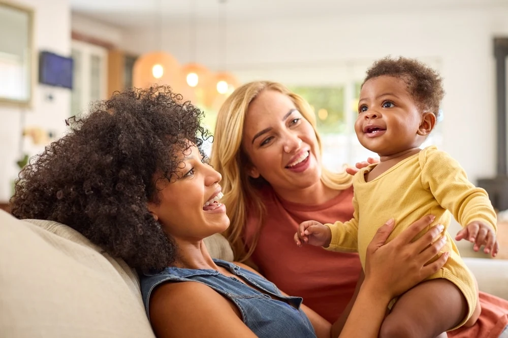 Nanny and mother smiling together with a happy baby in a warm home setting