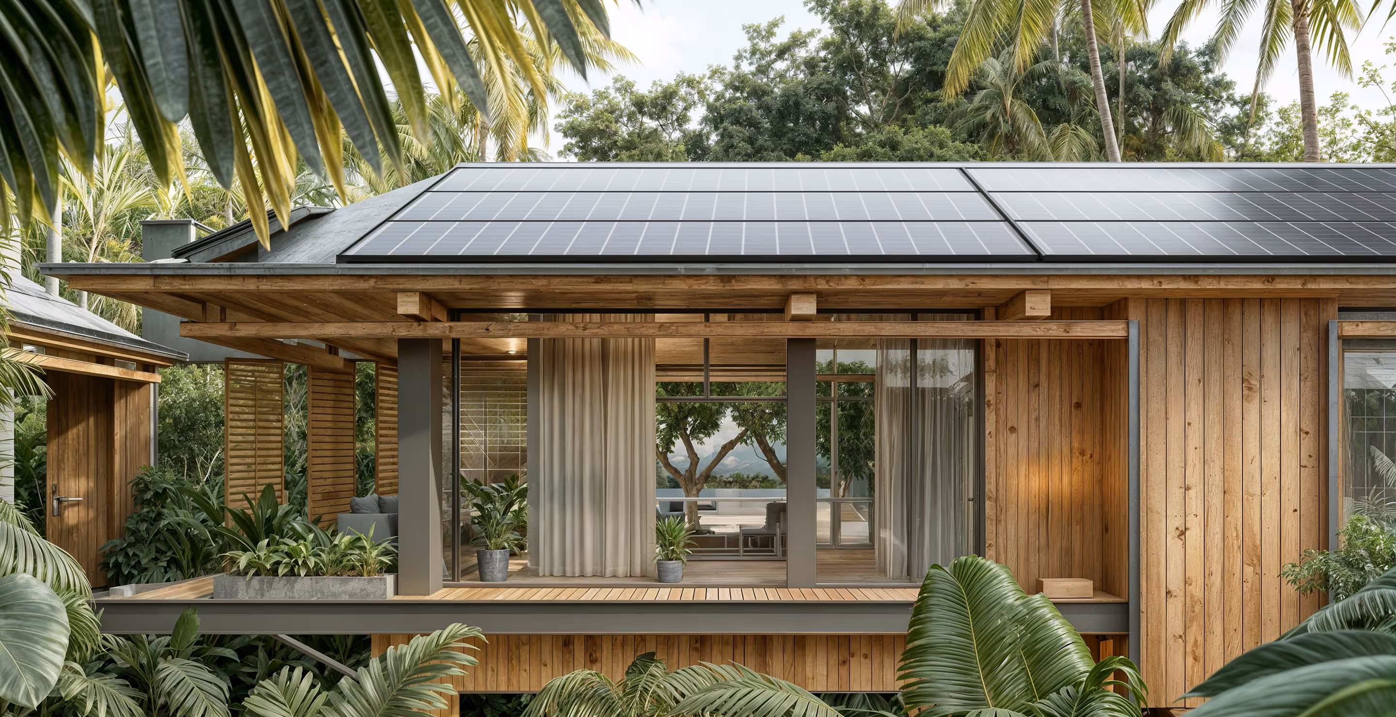 Современный деревянный дом с солнечными панелями на крыше, окруженный тропическими растениями.