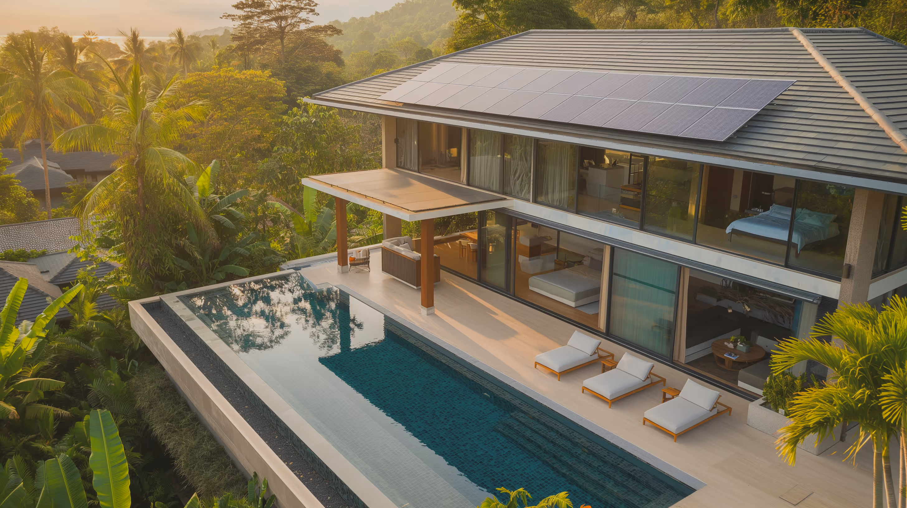 Современный двухэтажный дом с солнечными панелями на крыше и бассейном на террасе на фоне тропической растительности.